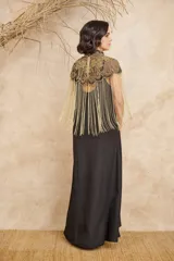 Capa negra con cuello alto y bordados dorados. Presenta flecos largos dorados que caen desde los hombros.