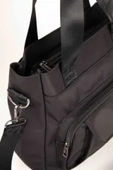 Cartera negra con asas fijas y correa regulable y desmontable con el logo de la marca. Cuenta con tres bolsillos externos, dos delanteros y uno trasero. En su interior tiene dos bolsillos adicionales.