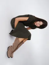 Botas de caña alta estilo western, confeccionadas en cuero color marrón oscuro. Presentan un diseño con puntera cuadrada, taco bajo de madera y una correa decorativa con hebilla metálica en la zona del tobillo.