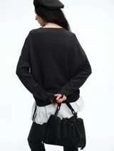 Sweater de punto color negro, con cuello redondo, hombros caídos y terminaciones acanaladas en puños y ruedo. Presenta un diseño de calce relajado y tejido suave.