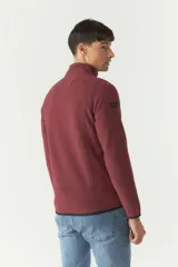 Campera polar gris de poliéster con cuello elevado, cierre frontal, bolsillos laterales con cierre y logo estampado en el pecho.