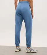 Pantalón tipo jogger de mujer, confeccionado en tejido modal con mezcla de poliéster y elastano. Presenta cintura elástica con lazo de ajuste, bolsillos laterales y puños elásticos en el ruedo.