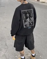 Buzo negro de cuello redondo con estampa en la espalda en formato de estampilla que muestra a una persona sosteniendo un gato.