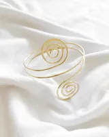 Brazalete dorado de metal con diseño espiralado.