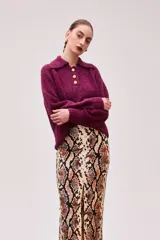 Sweater burdeo de punto con cuello polo, manga raglán, calce relajado y pretina ancha. Tiene tres botones dorados en forma de hoja.