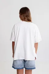 Remera blanca oversize de algodón con estampado de frutas y texto en el frente, pespuntes a contratono y tajos laterales.