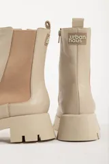 Bota tipo chelsea de caña media, color beige, con paneles laterales elásticos y suela track de plataforma dentada.