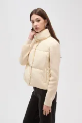 Campera híbrida con cuerpo delantero acolchado tipo puffer y mangas de tejido de punto acanalado con cuello alto. Presenta un diseño corto y holgado con cierre frontal oculto.