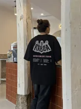 Remera oversize gris con efecto acid wash y estampa frontal con la leyenda "WORLDWIDE TOUR" en tipografía gótica.