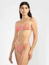 Bikini de dos piezas con estampado animal print en tonos rosado y naranja. El corpiño es de breteles finos y se ata en la espalda. La bombacha es de tiro bajo con cobertura mínima.