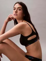 Corpiño deportivo Calvin Klein de algodón modal, color negro, con copas suaves sin relleno, tirantes ajustables y banda elástica inferior con logo multicolor en degradé.