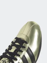 Zapatillas Adidas Tokyo doradas con detalles en negro, de cuero suave y silueta de perfil bajo.