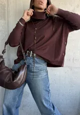 Sweater de tejido de punto color chocolate, con cuello polera, mangas largas con puños acanalados y diseño holgado con aberturas laterales y detalle de botones.