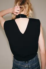 Top de punto negro sin mangas con cuello subido, hombreras y espalda descubierta.