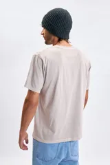 Remera de manga corta con efecto lavado, color gris claro, con estampado tipográfico minimalista en el pecho.