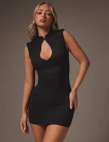 Vestido mini ajustado negro, sin mangas, con cuello estilo mao y una llamativa abertura frontal en forma de gota en el pecho.