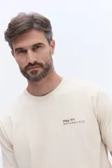 Remera de manga corta color beige, con cuello redondo y estampado de lettering en el pecho.