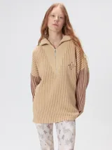 Pullover de tejido acanalado grueso con diseño bicolor en tonos marrón y bordó. Presenta cuello alto con cierre frontal, mangas largas y corte holgado.