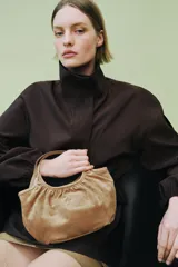 Bolso de hombro formato mini shopper confeccionado en piel de ante, con diseño fruncido, doble asa de mano y cierre mediante clip metálico.