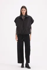 Chaleco acolchado negro con diseño de rombos, cierre frontal con cremallera y bolsillos laterales.