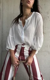 Camisa blanca de tejido liviano y fresco, con calce suelto, cuello de inspiración romántica y mangas amplias con frunces.