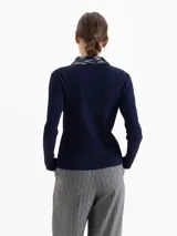 Top de punto acanalado color azul marino, con mangas largas y cuello camisero bordado con lentejuelas al tono. Presenta cierre frontal con broches metálicos.