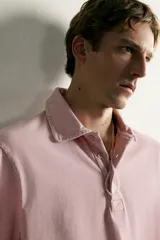Polo de corte regular fit en color rosado con efecto lavado. Presenta cuello solapa, cierre frontal de botones y mangas cortas con acabados en rib.