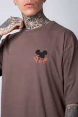 Remera negra de algodón de corte oversize, con mangas cortas y cuello redondo. Estampado pequeño en el frente y diseño grande en la espalda con Mickey Mouse y caracteres orientales en tonos rojizos.