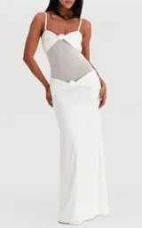 Vestido largo blanco de corte sirena con diseño strapless, cuerpo drapeado con nudo central y sección semitransparente en el torso.