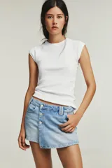 Falda pantalón de tiro alto confeccionada en denim, con diseño cruzado y cierre frontal mediante botones metálicos. Cuenta con cinco bolsillos y trabillas para cinturón.