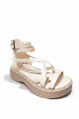Sandalias de plataforma con tiras cruzadas en el empeine y ajuste de pulsera con hebilla en el tobillo. Presentan una suela de plataforma de goma en tono beige y cuerpo en color blanco.
