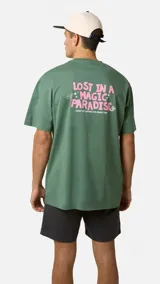 Camiseta verde de corte oversize, con estampado gráfico en la espalda con la leyenda "Lost in a Magic Paradise" en letras rosadas.