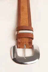 Cinto de diseño artesanal combinado en cuero liso y gamuza, con hebilla metálica plateada de estilo western.