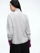 Sweater de cuello alto con textura peluda, confeccionado en tejido de punto suave y holgado, con mangas largas y puños ajustados.