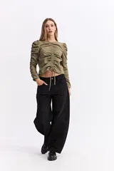 Blusa de manga larga color marrón chocolate, con diseño fruncido central ajustable mediante cordones y mangas con detalle de frunces laterales que aportan volumen.