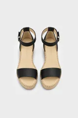 Sandalias de tacón en cuña forrada en yute trenzado, con capellada de cuero negro, tira en el talón y tira ajustable al tobillo con hebilla metálica.