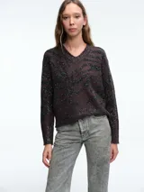 Sweater de punto con escote en V, manga larga y diseño holgado. Presenta un estampado animal print con aplicaciones de lentejuelas brillantes en tonos oscuros.