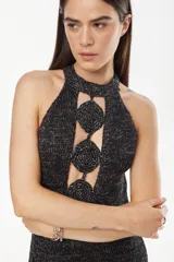 Vestido largo tejido de punto con escote halter, sin mangas y detalles de calados circulares unidos en el centro del pecho. Confeccionado en mezcla de algodón, acrílico y lurex.