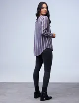 Camisa estampada con rayas verticales blancas sobre fondo gris, cuello con solapa, escote en V y abertura central con botones.