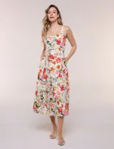 Vestido midi evasé de lino estampado con diseño floral multicolor sobre base beige. Cuenta con escote cuadrado, tirantes anchos y cierre invisible en la espalda.