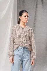 Blusa de gasa a cuadros en tonos beige y marrón, con escote en V adornado con volados en cascada, mangas largas con puños elásticos y ajuste holgado.