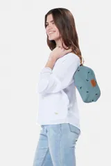 Estuche necessaire de lona tipo canvas color crudo con estampado de flores en color lila. Tiene cierre superior con tirador de cuero marrón y manija lateral de cuero marrón.