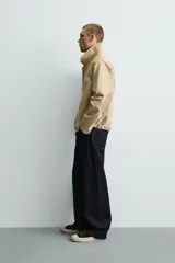 Cazadora relaxed fit de Zara confeccionada en denim de algodón color beige, con cuello de solapa en piel combinada, bolsillos con cremallera en el pecho y cierre frontal oculto.