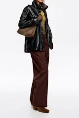 Bolso bandolera de tamaño mediano confeccionado en nylon negro, con estructura blanda, asa regulable de tejido, logo metálico de la marca en el frente y cierre con cremallera.