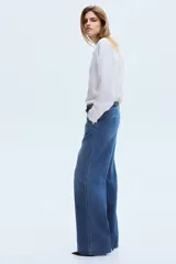 Jean de denim de algodón rígido, color azul con efecto lavado, de tiro alto y corte recto holgado. Cuenta con bolsillos al bies y pliegues marcados al frente y en la espalda.