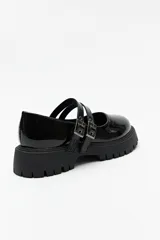 Guillerminas negras de cuero sintético charolado, con plataforma chunky y doble tira ajustable con hebillas metálicas.