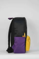 Mochila de nylon con diseño tricolor: negro en la parte superior, amarillo en el bolsillo frontal y morado en los laterales. Presenta el logo de la NBA en la parte superior y el logo de Los Angeles Lakers en el bolsillo frontal. La espalda es de tela mesh.