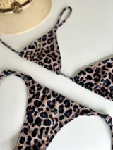 Conjunto de bikini con estampado animal print, compuesto por un corpiño triangular con tiras largas para atar en la cintura y una bombacha colaless con tiras para atar en los costados.