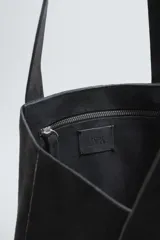 Bolso tipo shopper fabricado en cuero con acabado serraje color gris oscuro. Compartimento principal sin cierre con bolsillo interior con cremallera. Dos asas de mano fabricadas en cuero.
