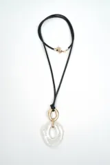 Collar largo con cordón negro y un dije colgante de resina marmolada blanca con detalles metálicos dorados.